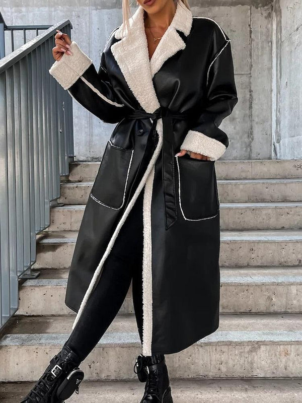 femme blonde portant un manteau lon en simili cuir noir et fausse fourrure blanche fermé par une ceinture en simili cuir noir